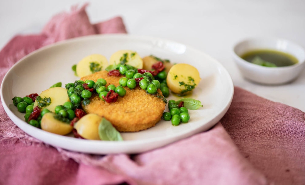 Cotoletta con piselli, patatine novelle e pomodori secchi al pesto vegetale